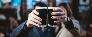Couple holding up 2 pints of dark beer