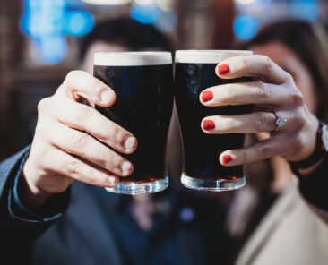 Couple holding up 2 pints of dark beer