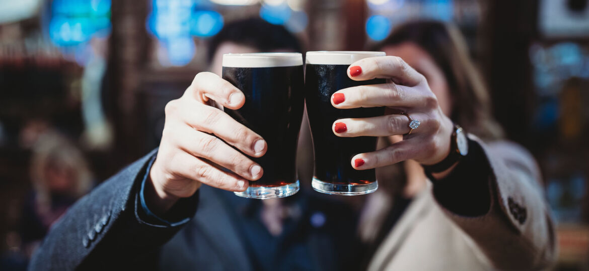 Couple holding up 2 pints of dark beer