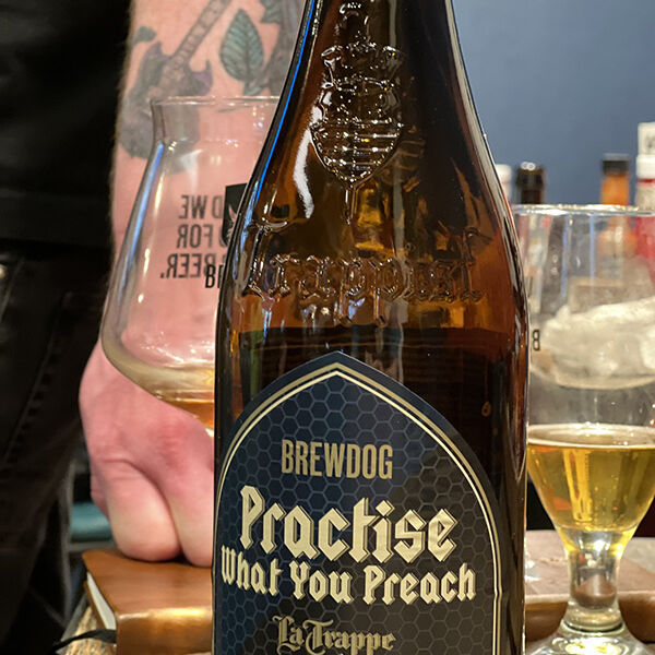 Bottle of Trappist beer on table with glasses in background