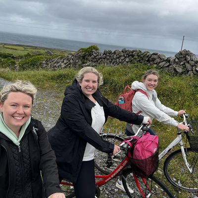 3 happy female beer trippers walking bikes on the coast of ireland