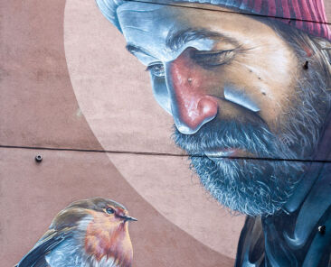 large scale mural of man with bird on the side of a building
