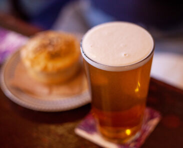 pint of beer next to a meat pie