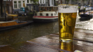 pint of beer on a table with Amsterdam canals in background