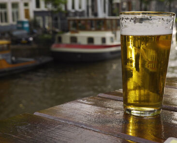 pint of beer on a table with Amsterdam canals in background