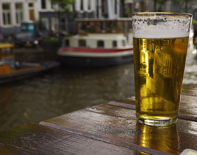 pint of beer on a table with Amsterdam canals in background