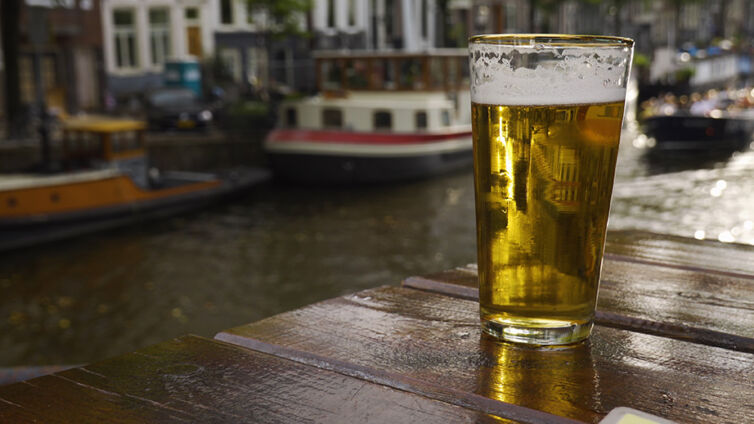 pint of beer on a table with Amsterdam canals in background
