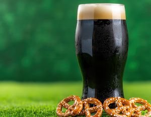 dark beer on green background with pretzels